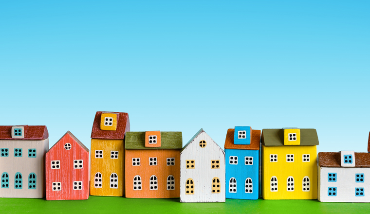 Colorful miniature houses arranged in a row on blue background. Urban city background banner. Copy space
