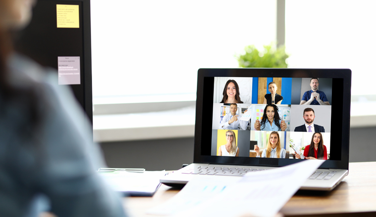 Woman talking with international colleagues using online video chat service at workplace closeup