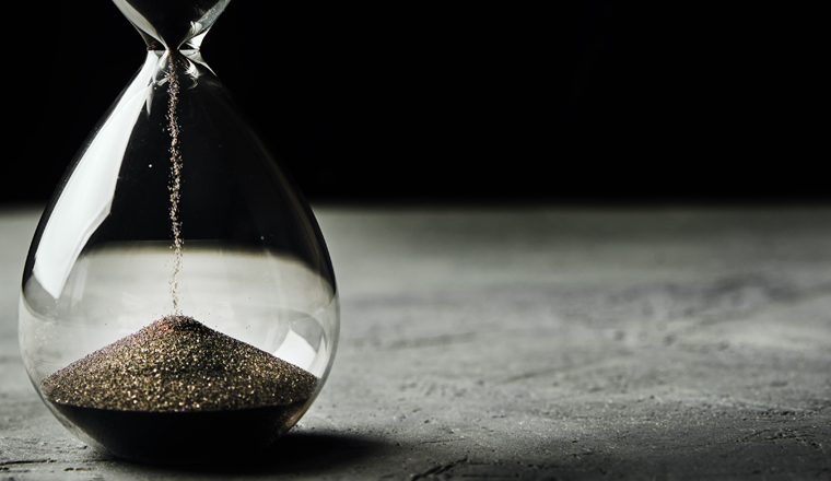 Hourglass on dark background, long banner. Urgency and running out of time concept