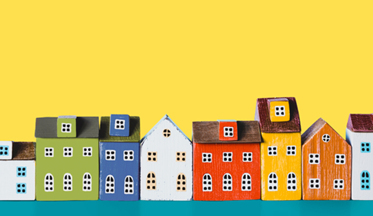 Colorful miniature houses arranged in a row on yellow background. Urban city background banner. Copy space