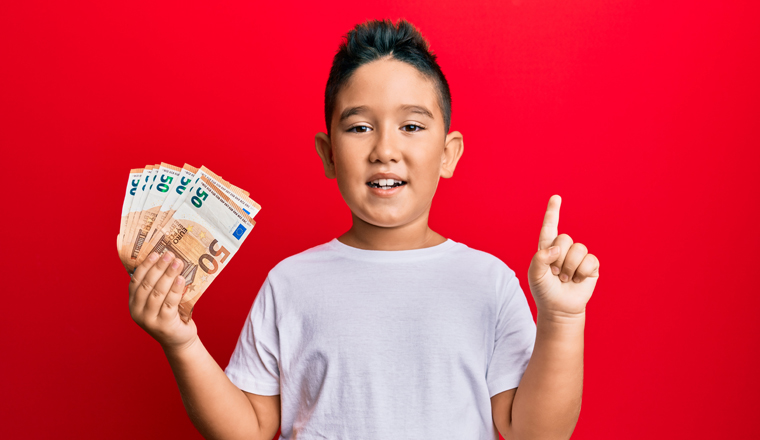 Little boy hispanic kid holding bunch of 50 euro banknotes smiling with an idea or question pointing finger with happy face, number one 