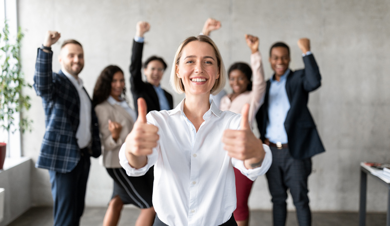 Successful Business Team. Businesswoman Gesturing Thumbs Up Standing With Joyful Employees In Modern Office. Great Deal, Leadership And Teamwork Concept. Selective Focus