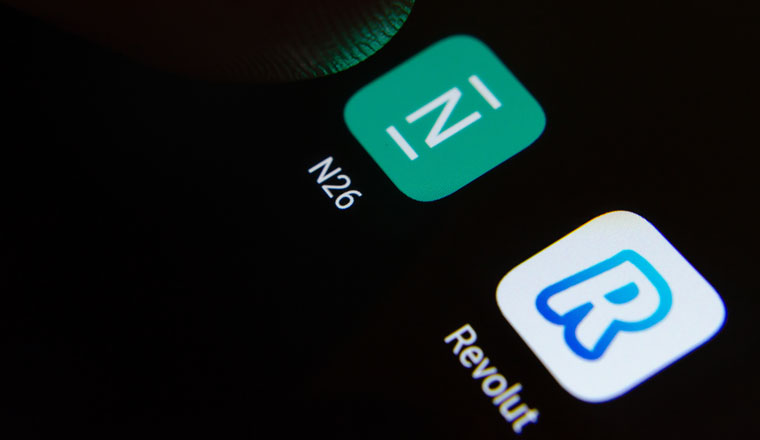 N26 and Revolut bank apps logo on the screen and a finger touching one of them. Concept photo for competition.