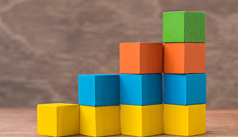 stack of colorful wood cube building blocks on wood background