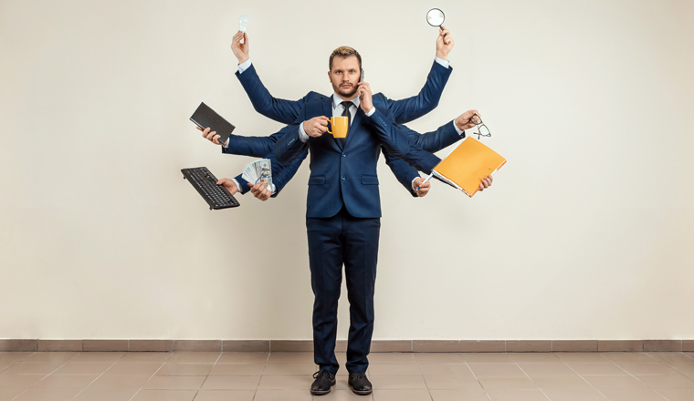 Businessman with many hands in a suit. Works simultaneously with several objects, a mug, a magnifying glass, papers, a contract, a telephone. Multitasking, efficient business worker concept