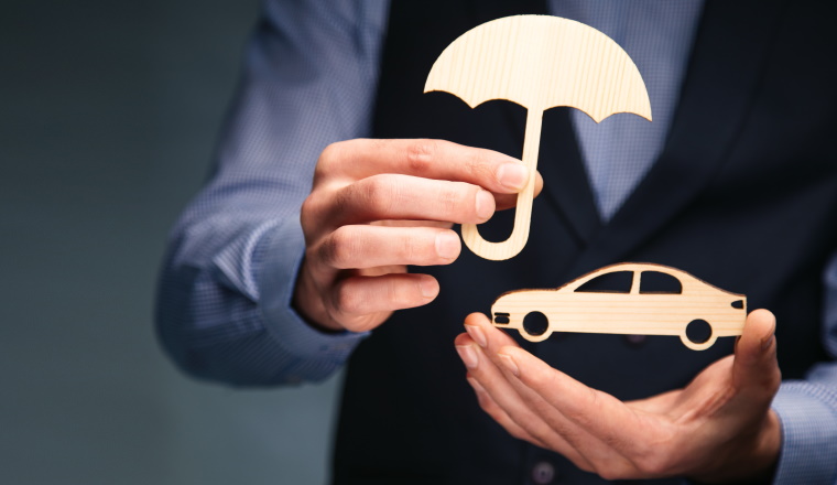 business man holding wooden umbrella with car