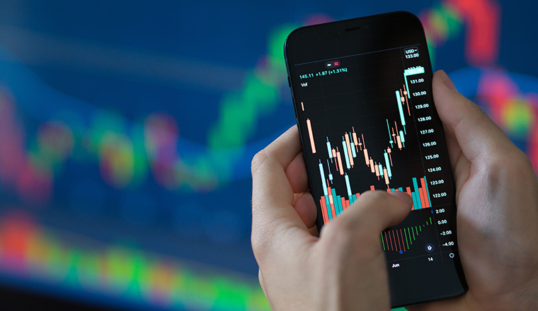 Close up shot of real time stock trading on smartphone with investing app which presents a candlesticks share price