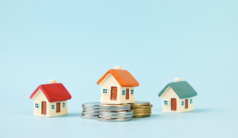 Miniature houses and stacks of coins. The concept of real estate, mortgage, home insurance, home purchase and sale.