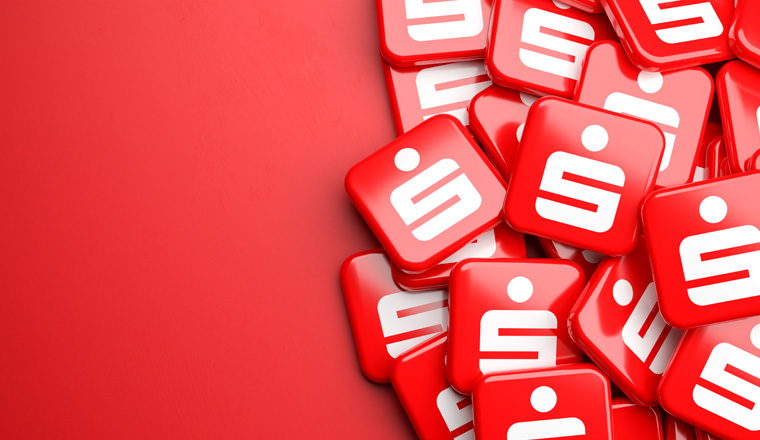 Logos of the German savings banks Sparkasse on a heap on a table. Copy space. Web banner format.