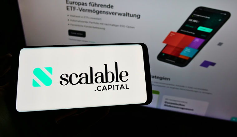 STUTTGART, GERMANY - Jun 14, 2021: Person holding mobile phone with logo of digital asset management company Scalable Capital on screen in front of web page. Focus on phone display.
