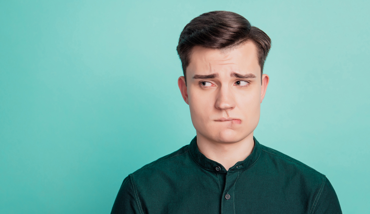 Portrait of doubtful minded smart guy look side empty space bite lip on turquoise background.