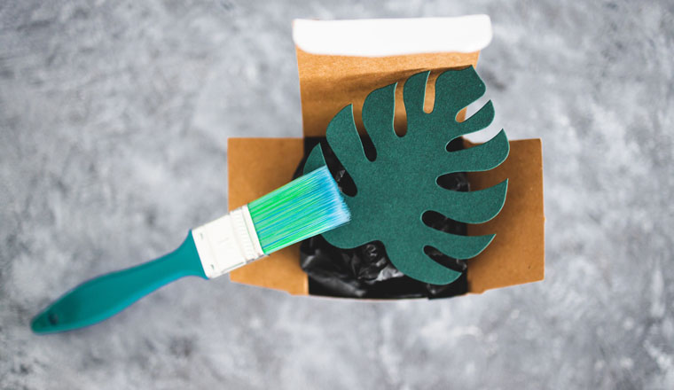 greenwashing and companies pretending to be sustainable conceptual image, paper leaf with green brush painting on it on top of product packaging