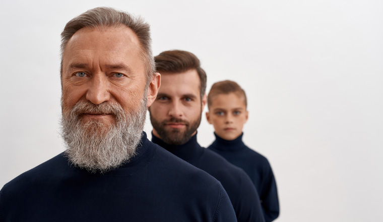 Portrait of three generations of Caucasian men. Old grey-haired grandfather forefront, adult young son and small grandson at back. Family bonding and unity. Offspring, descendant concept.