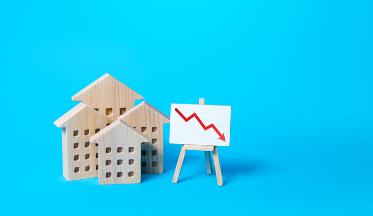 Residential buildings and down arrow graph on easel. Low property value, low price. Real estate market fall. Lower mortgage interest rates. Falling prices for rental. Affordable housing. Crisis