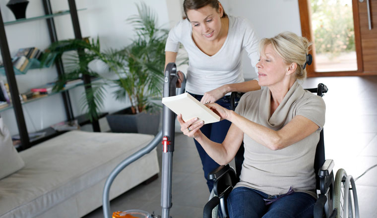 Young woman helping disabled lady at home