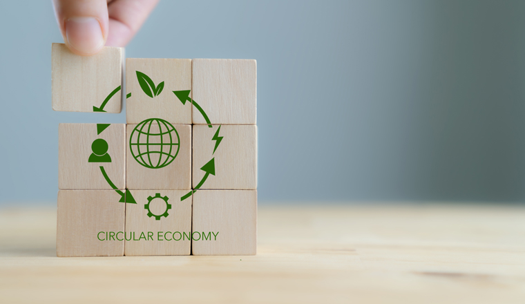 Circular economy concept, recycle, environment, reuse, manufacturing, waste, consumer, resource. Sustainable development. Hand put wooden cubes; the symbols of circular economy on grey background.