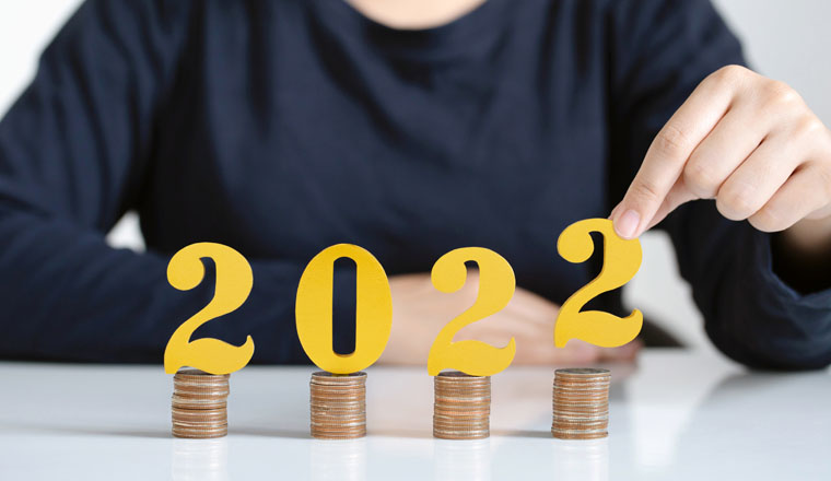 Female in black shirt hands putting gold wooden number 2022 on stack of coins. tax payment, investment and banking.2022 New year saving money and financial planning concept. 