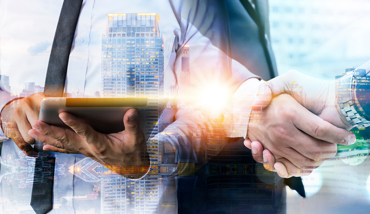 Double exposure of business handshake for successful of investment deal and business man using digital tablet, teamwork and partnership concept.