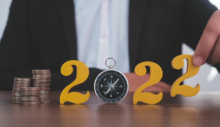 Man hands putting gold wooden number 2022 on the stack of coins compass, financial direction 2022. Tax payment, 2022 new year saving money and financial planning concept