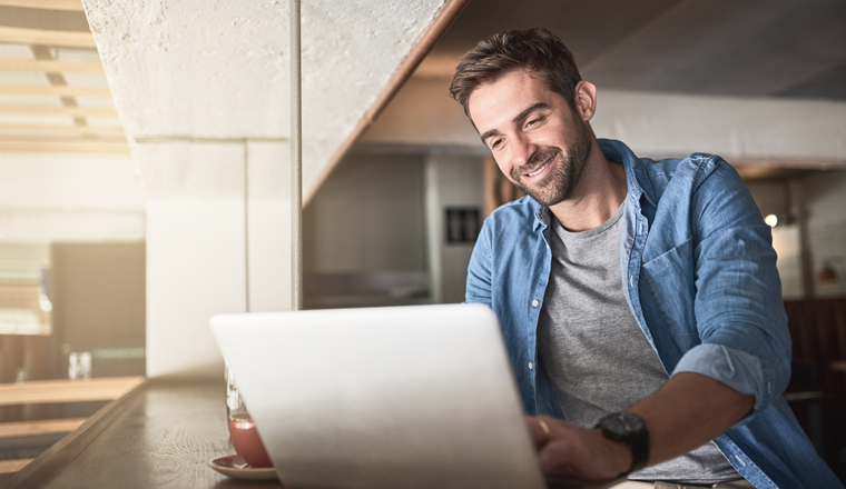 Shot of a handsome young man using a laptop in a coffee shop