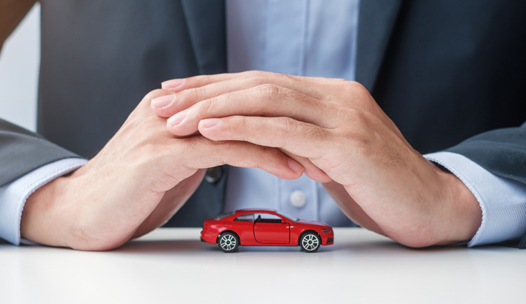 Businessman hand cover or protection red car toy on table. Car insurance, warranty, repair, Financial, banking and money concept