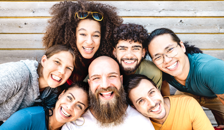 Multicultural guys and girls taking selfie outdoors on wooden background - Happy milenial life style concept with young multiethnic hipster people having fun day together - Warm bright filter