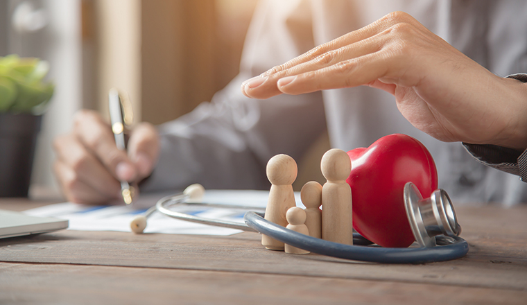 Hand protect family wooden doll for insurance planning protection and safety family health insurance concept.