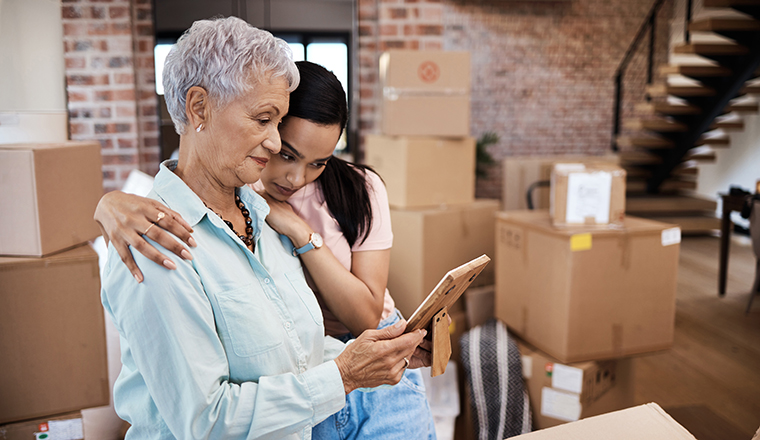 Shot of a senior woman looking at a photograph with her daughter while packing boxes on moving day.