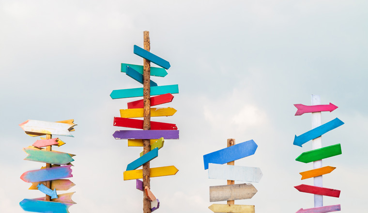 Colorful wooden direction arrow signs on wooden poles