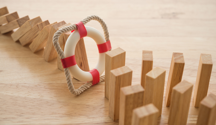 Lifebuoy stop wood block fall domino effect on office wooden table background. Life, health and property insurance business concept. Insurance is risk control management.