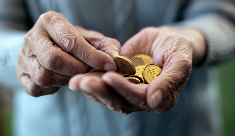 close-up of an older womans hand holding coins and counting