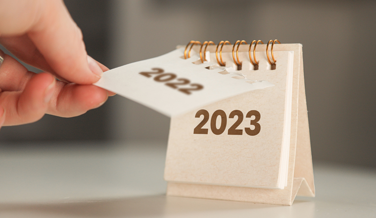 a woman's hand turns over a calendar sheet. year change from 2022 to 2023.