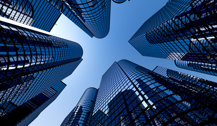 Low angle shot of modern glass city buildings with clear sky background.