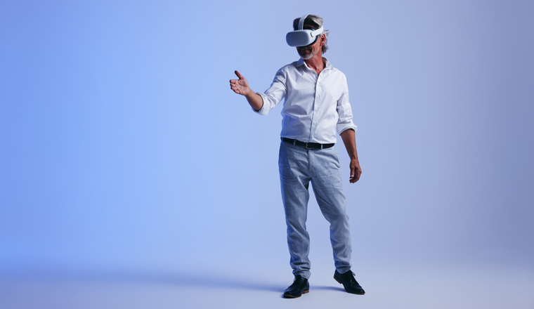 Mature businessman giving a virtual handshake in a studio. Senior businessman meeting a business partner in the metaverse. Cheerful businessman wearing a virtual reality headset.