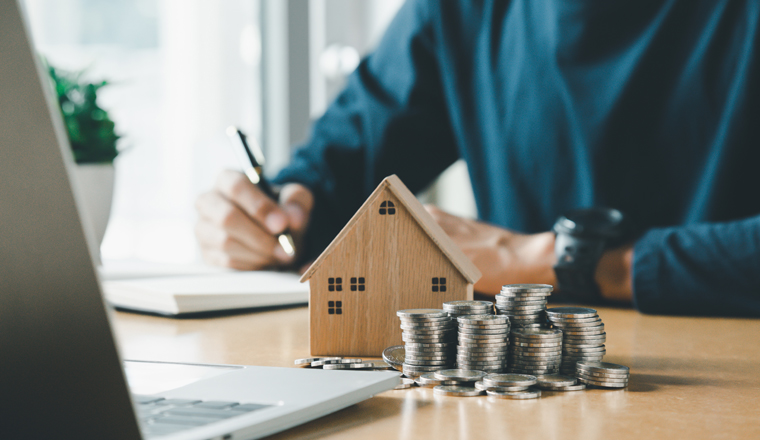 Man hand holding coin on wood table. Save money and financial investment and saving money for buying house, financial plan home loan concept.