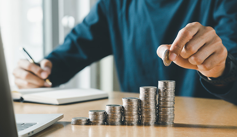 Hand putting coins in a piggy bank for save money and Saving Money concept.