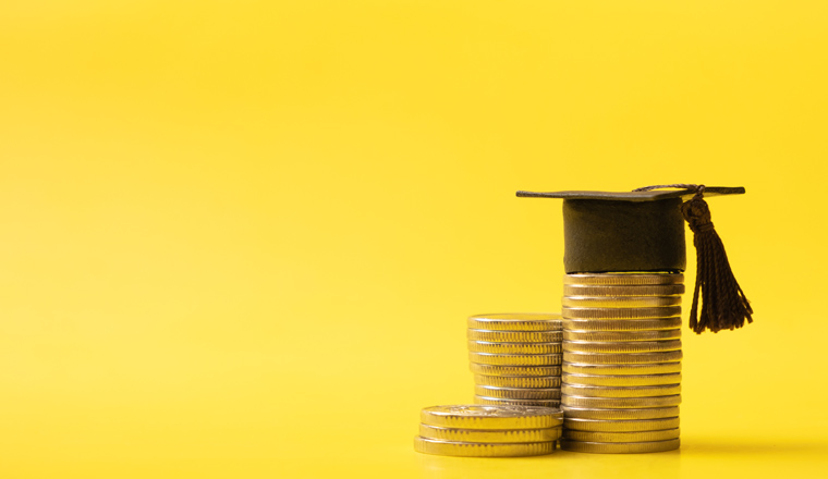 Graduated cap with coins on yellow background. Savings for education concept.