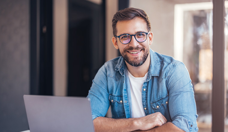 Portrait of attractive smiling man sitting in office and looking at camera. 