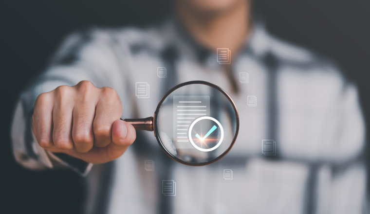 Businessman holding a magnifying glass, showing Audit Document concept,quality assessment management With a checklist, business document evaluation process, market data report analysis and consulting