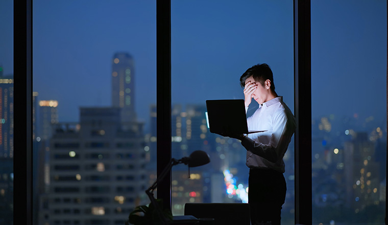 Asian business man frustrated standing in office using notebook hopelessly