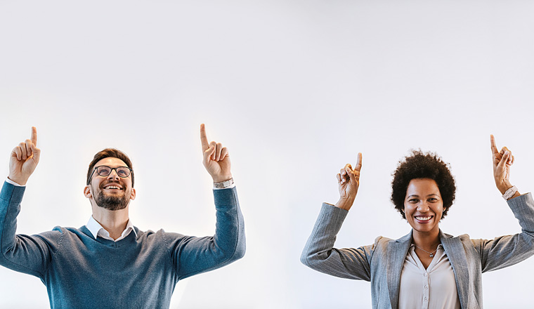 Interracial executives in smart casual are pointing up at the copy space.