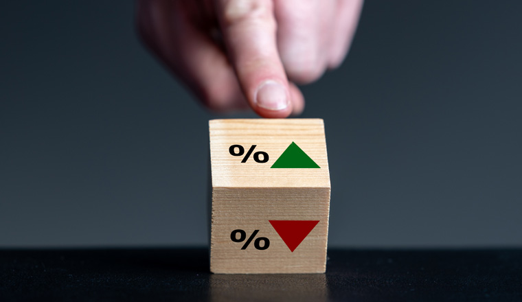 Symbol for the trend of the interest rate. Hand turns wooden cube and changes the orientation of an arrow from down to up.