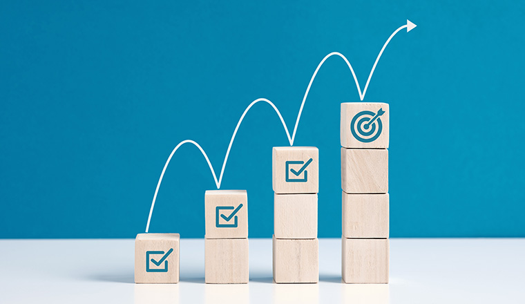 Steps for goal achievement and business success. Project tracking and task completion. Managing project timeline. Checkmark and target goal  symbols on wooden cubes.