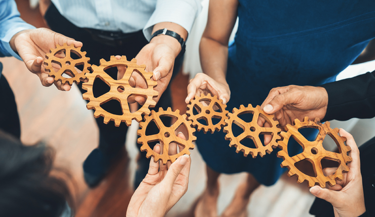 Office worker holding cog wheel as unity and teamwork in corporate workplace concept. Diverse colleague business people showing symbol of visionary system and mechanism for business success. Concord