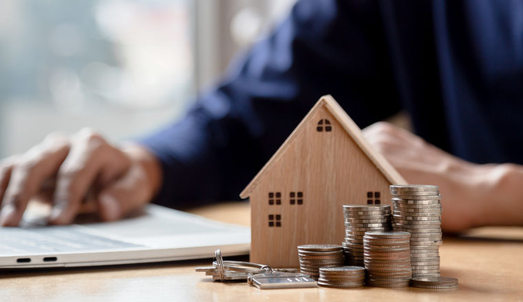 Businessman choosing mini wood house model from model and row of coin money on wood table, selective focus, Planning to buy property. Choose what's the best. A symbol for construction ,ecology, loan concepts.