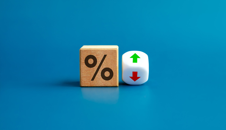 Percentage icon on wooden cube block and up and down arrow symbol on flipping white dice on blue background. Interest rate, financial stocks, ranking, GDP percent change, money exchange concepts.