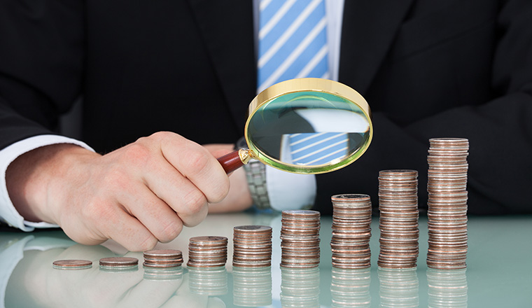 Midsection of young businessman examining coins stacked as bar graph at office table