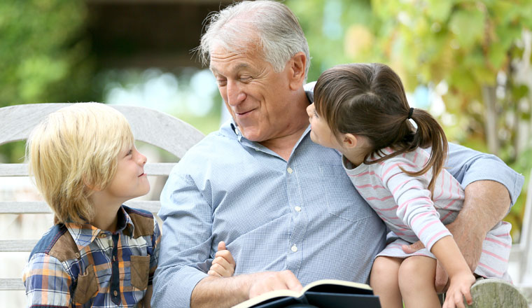 Senior man reading book with grandkids