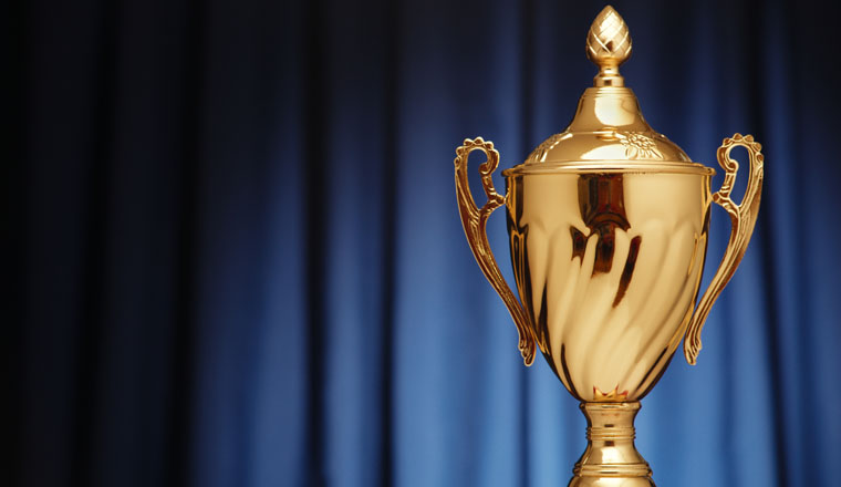 Golden glowing trophy cup on a dark blue background