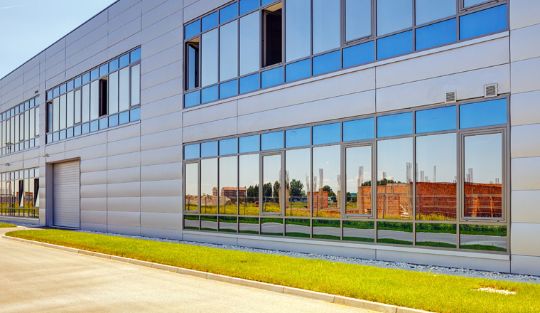 Details of gray facade made of aluminum panels  with doors and windows on industrial building